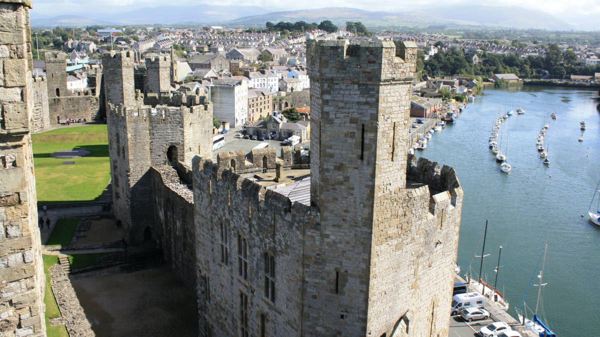The walls of Caernarfon Castle with boats in the adjoining harbour